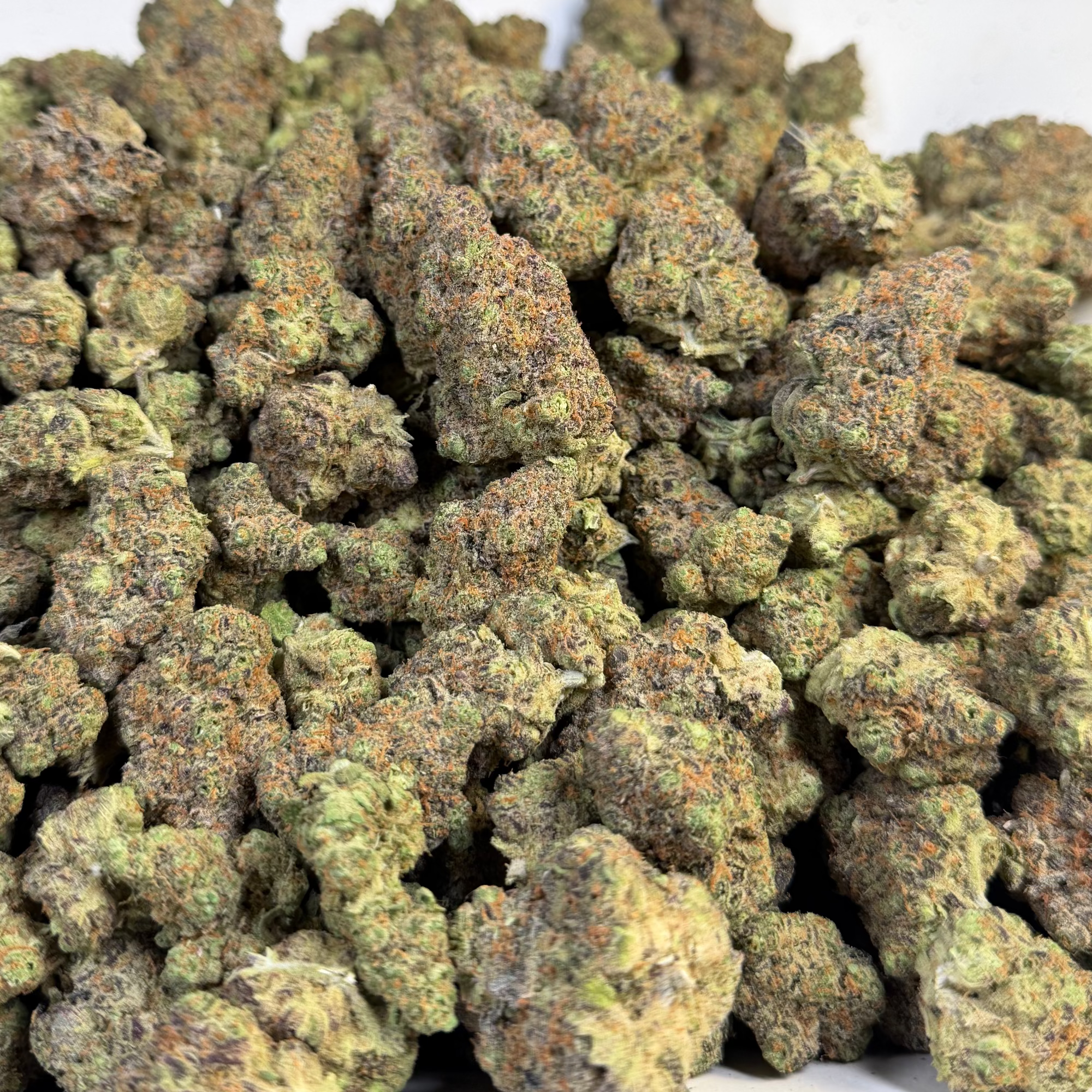 Close-up of cannabis buds on a white plate with 'Cotton Candy Cookies' label in the background.
