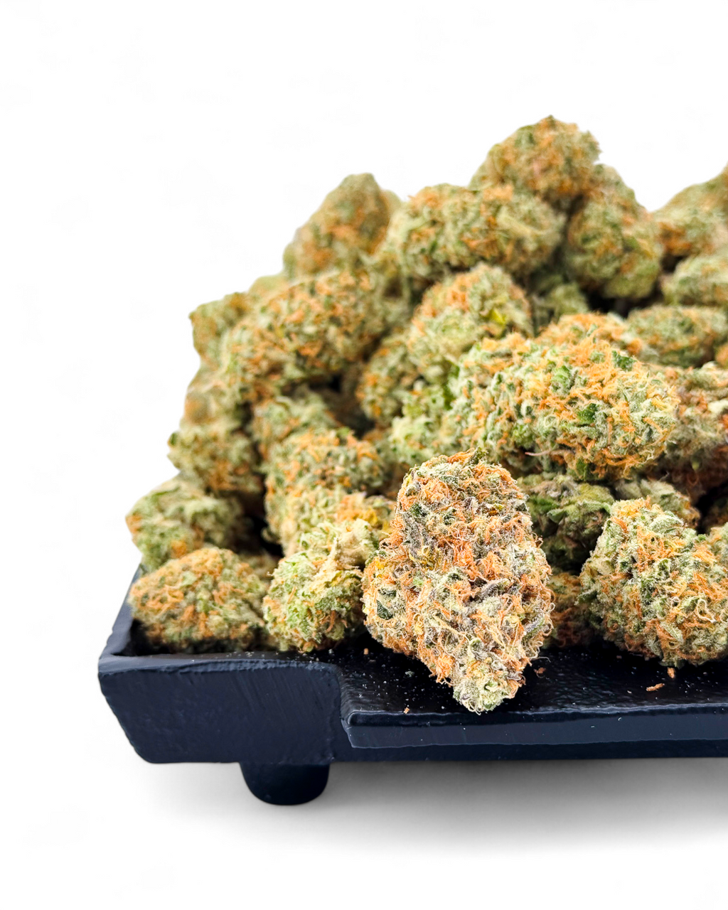 Close-up of cannabis buds on a black tray with a white background