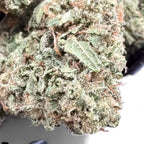 Close-up of a cannabis bud with green leaves and white trichomes.