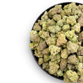 Black bowl filled with green cannabis buds on a white background