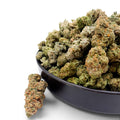 Dr. Wonderstone Alien Wedding THCa flower buds in a black bowl, featuring dense green nugs with orange pistils.