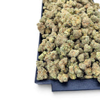 Dr. Wonderstone Banana Zkittlez THCa flower featuring dense, frosted green buds with orange pistils on a black tray.
