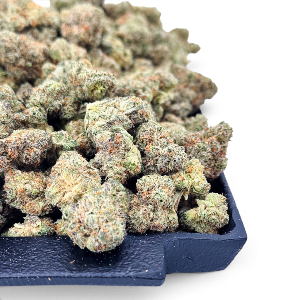 Dr. Wonderstone Banana Zkittlez THCa flower with dense, frosted green buds and orange pistils on a black tray.