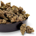 Dr. Wonderstone Blueberry Muffin THCa flower buds in a black bowl, featuring dense, sugar-coated green indica nugs.