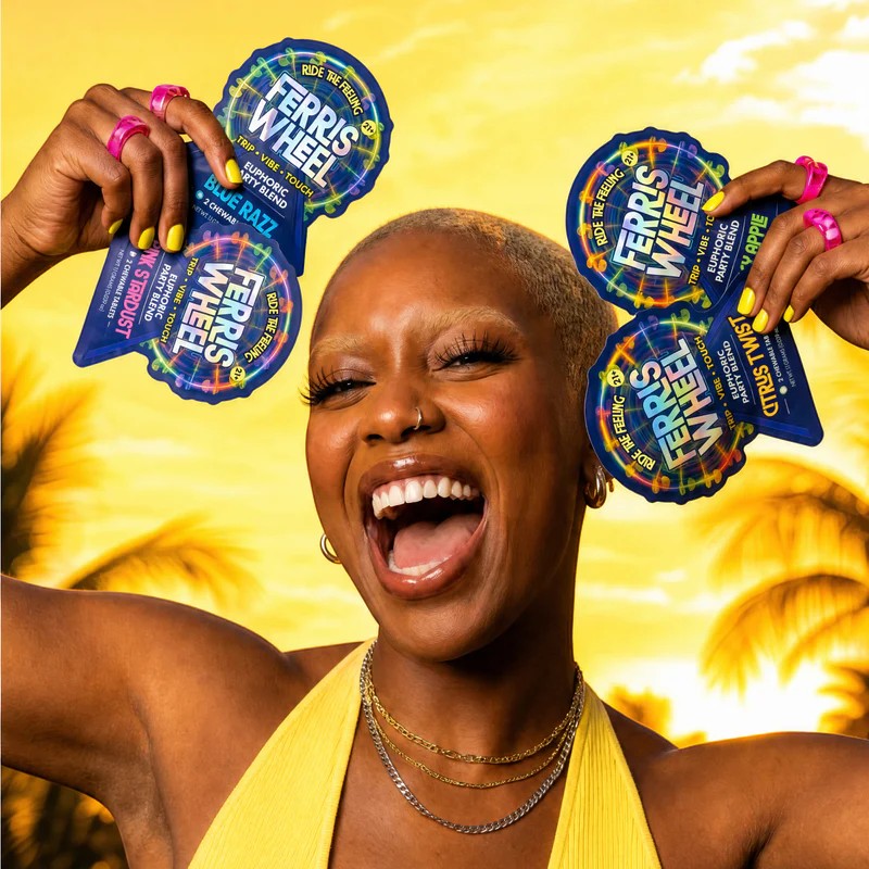 Dr. Wonderstone model smiling while holding colorful Ferris Wheel chewable tablet pouches against a sunset background.