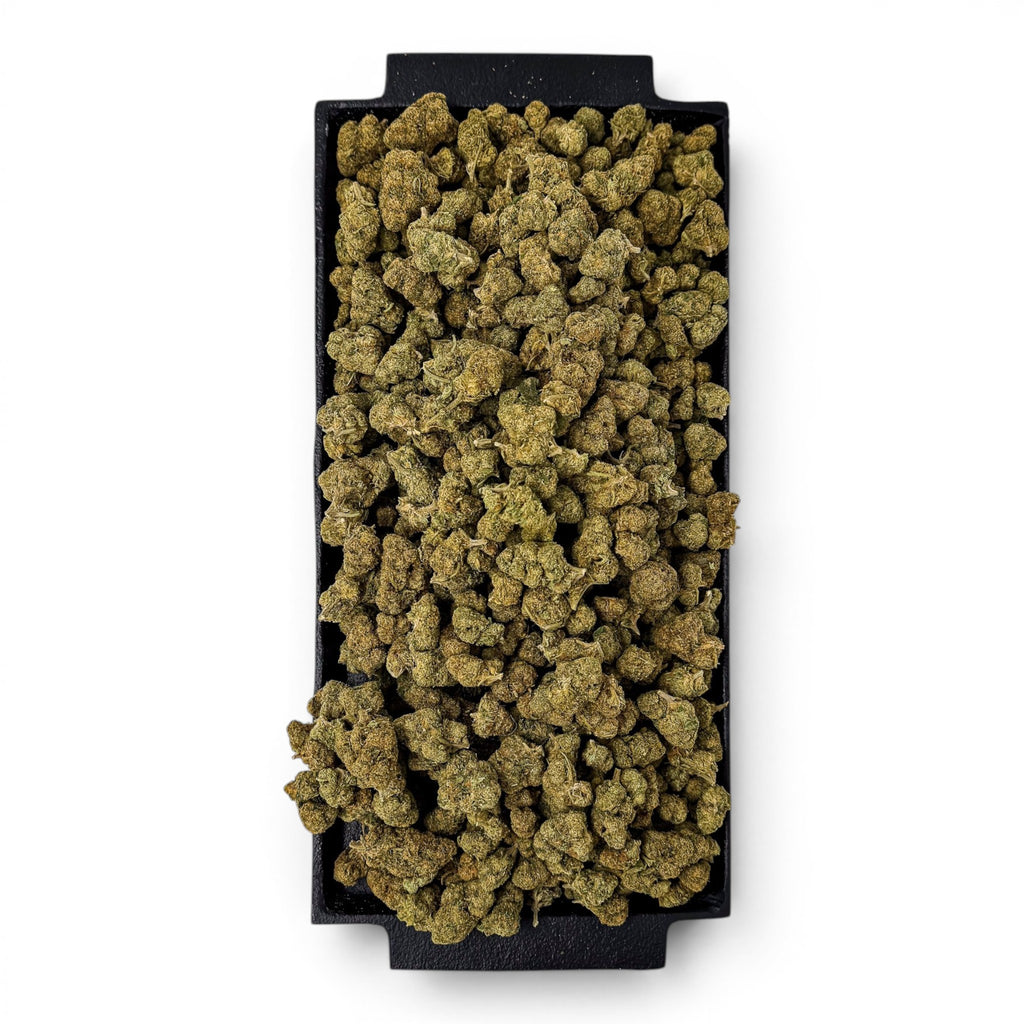 Dr. Wonderstone Green Crack THCa flower buds piled on a black rectangular tray, showcasing dense, earthy green nugs.