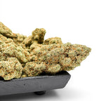 Dr. Wonderstone London Pound Cake THCa flower buds with frosty green texture in a black tray on white background.
