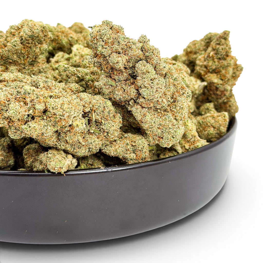 Dr. Wonderstone London Pound Cake THCa flower buds in a black bowl, featuring dense, frosty green and orange nugs.