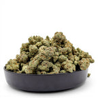 Dr. Wonderstone Modified Grapes THCa flower buds in a black bowl, featuring dense green and purple resinous nugs.