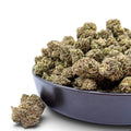 Dr. Wonderstone Oreoz THCa flower buds in a black bowl, featuring dense green nugs with orange pistils.