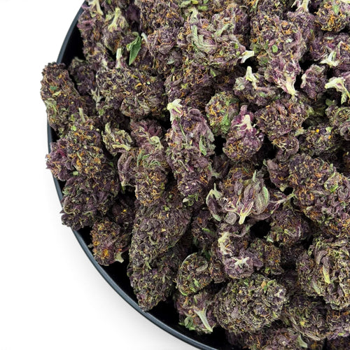 Dr. Wonderstone Tropical Cookies THCa flower featuring dense, deep purple buds with orange pistils in a black bowl.