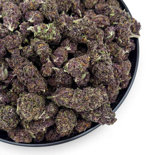 Dr. Wonderstone Tropical Cookies THCa flower featuring dense, dark purple buds with orange pistils in a black bowl.