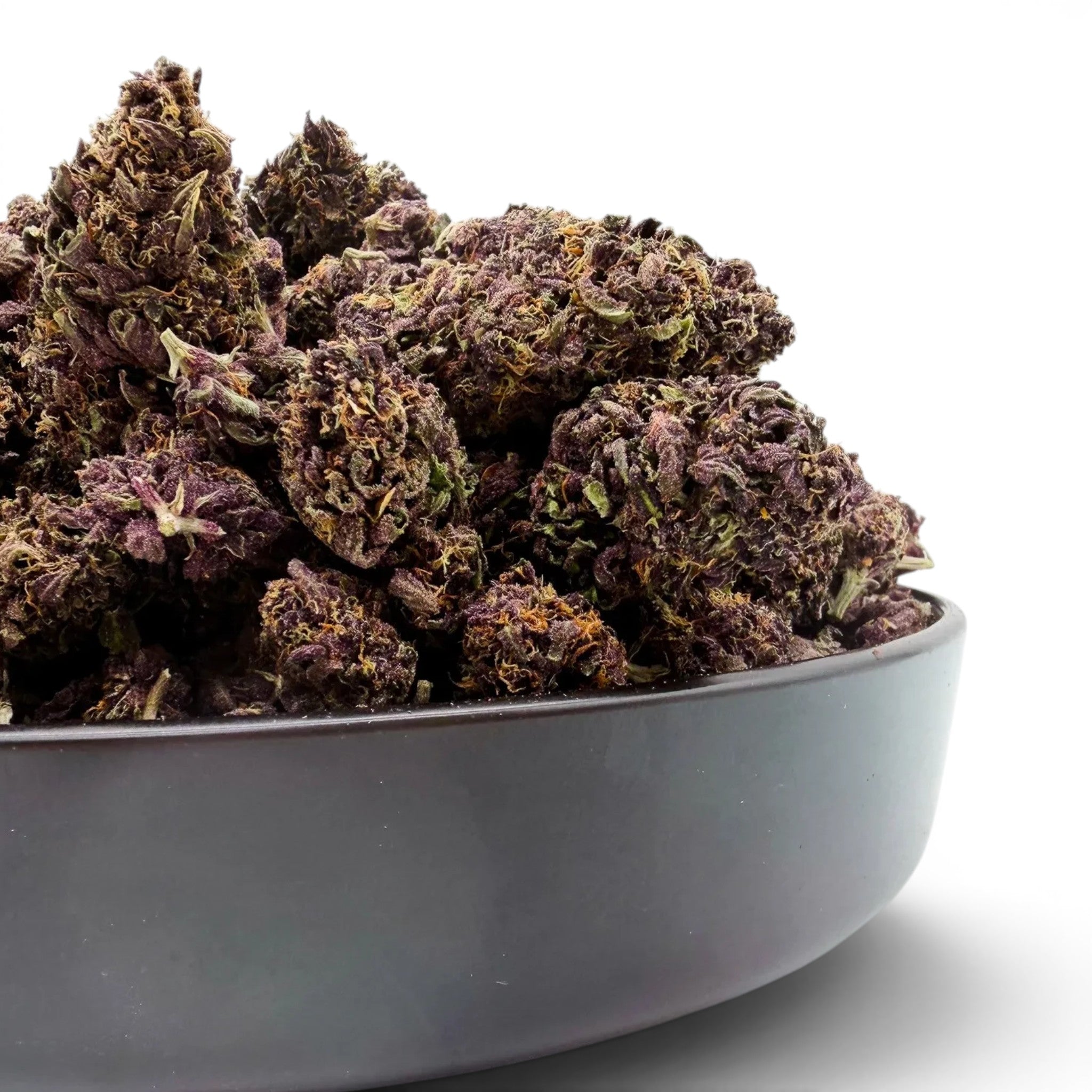 Dr. Wonderstone Tropical Cookies THCa flower in a bowl, featuring dense, sticky, deep purple buds with trichomes.
